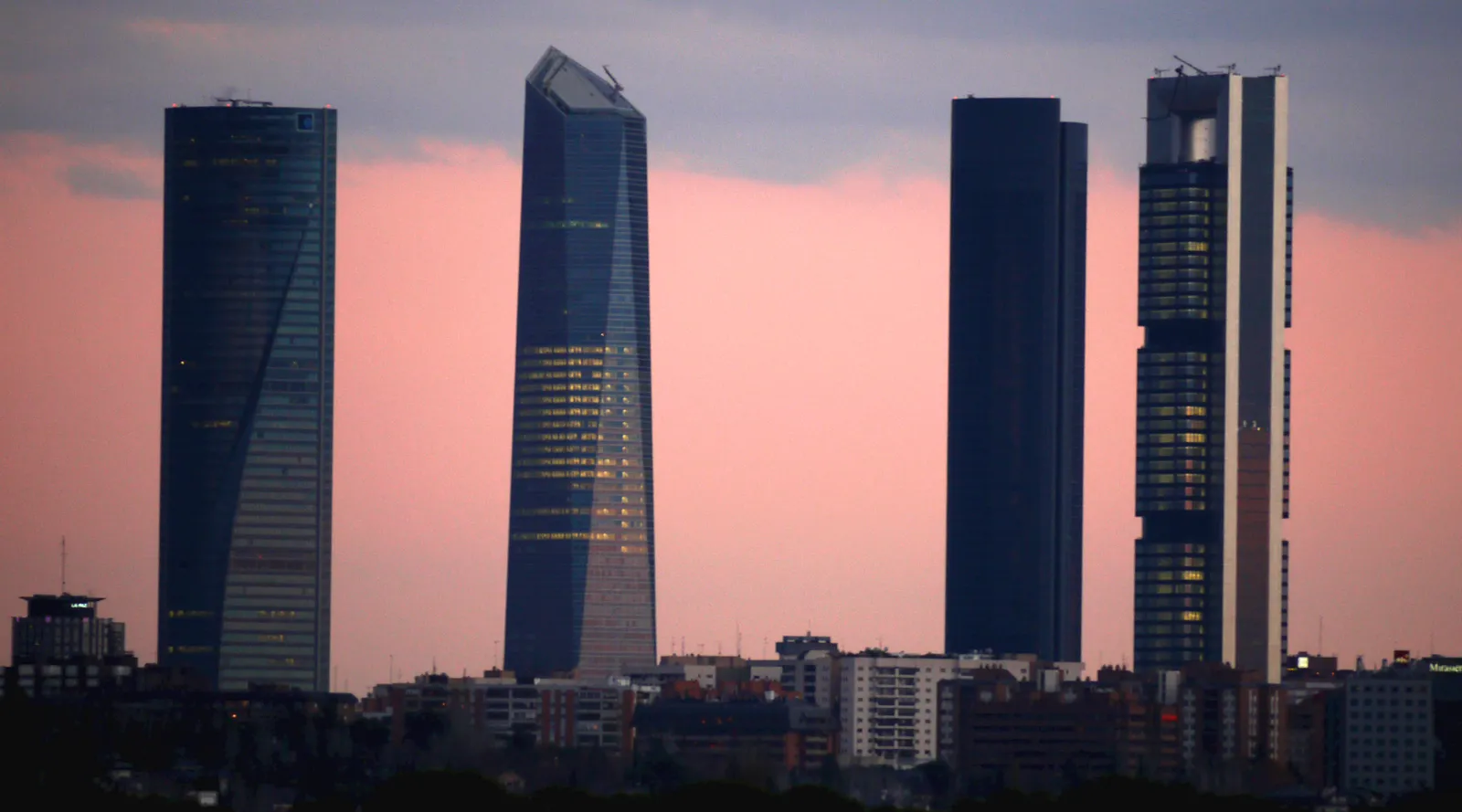 The Cuatro Torres Business Area towers in Madrid at dusk.