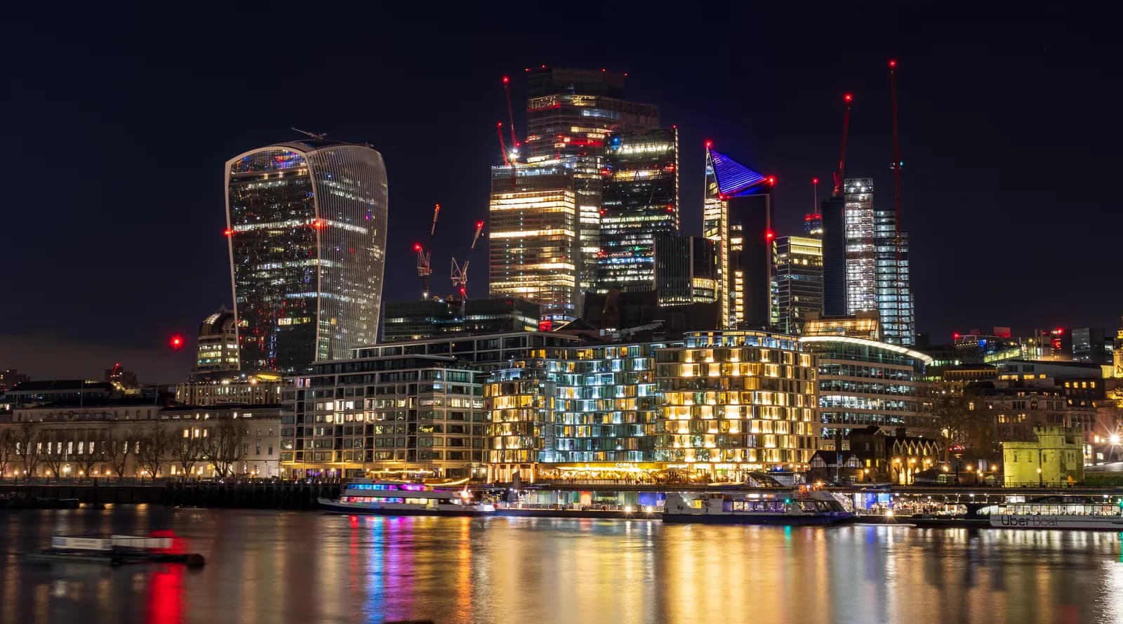 The City of London's towers at night, seen across the Thames.